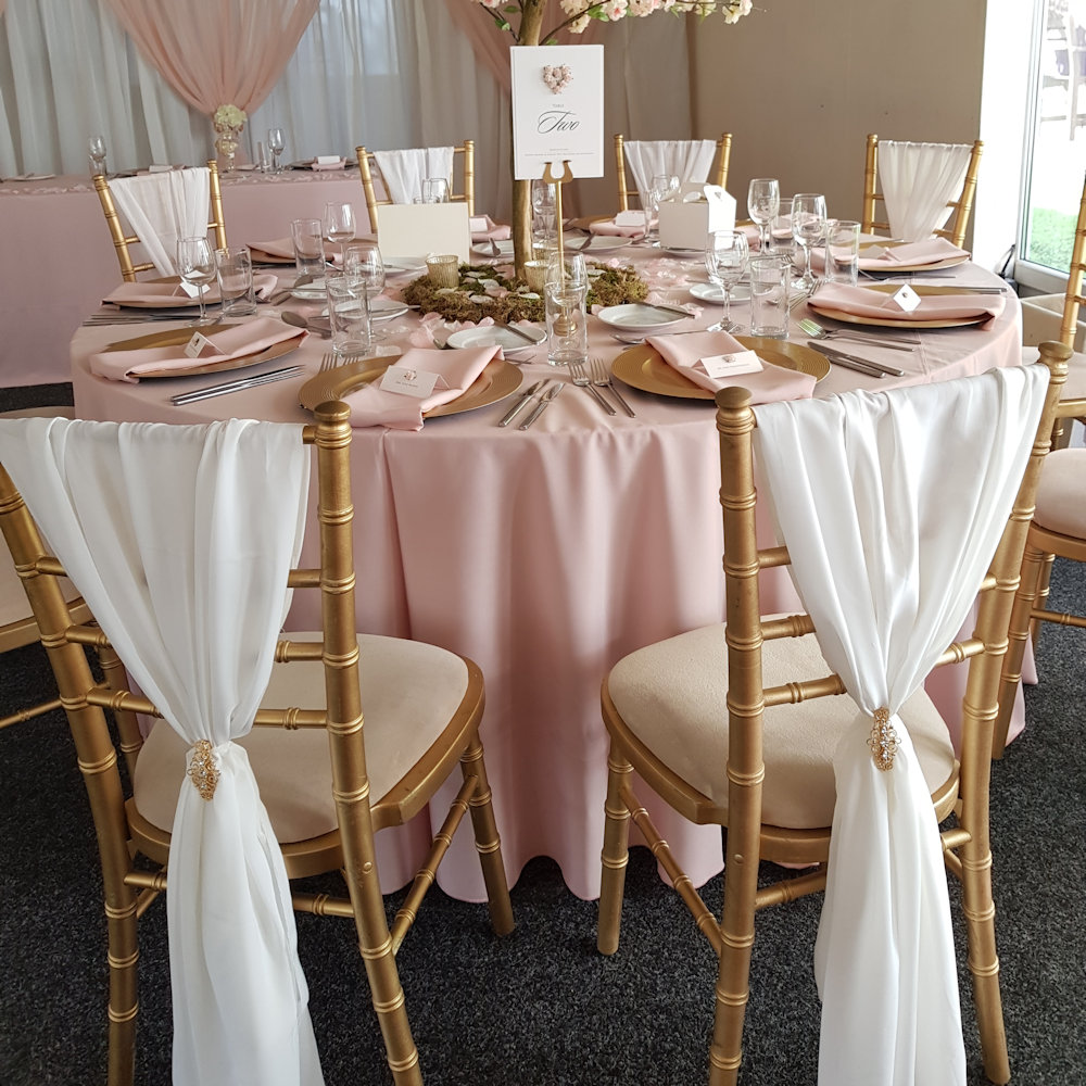 White chiffon chair drape with gold chiavaric chairs