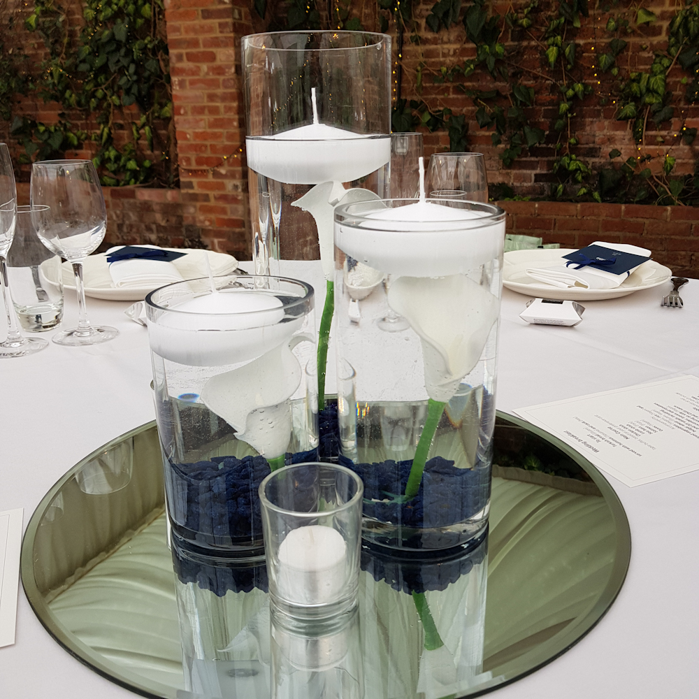 Cylinder vase centrepiece mirror calla lillies floating candles navy stones