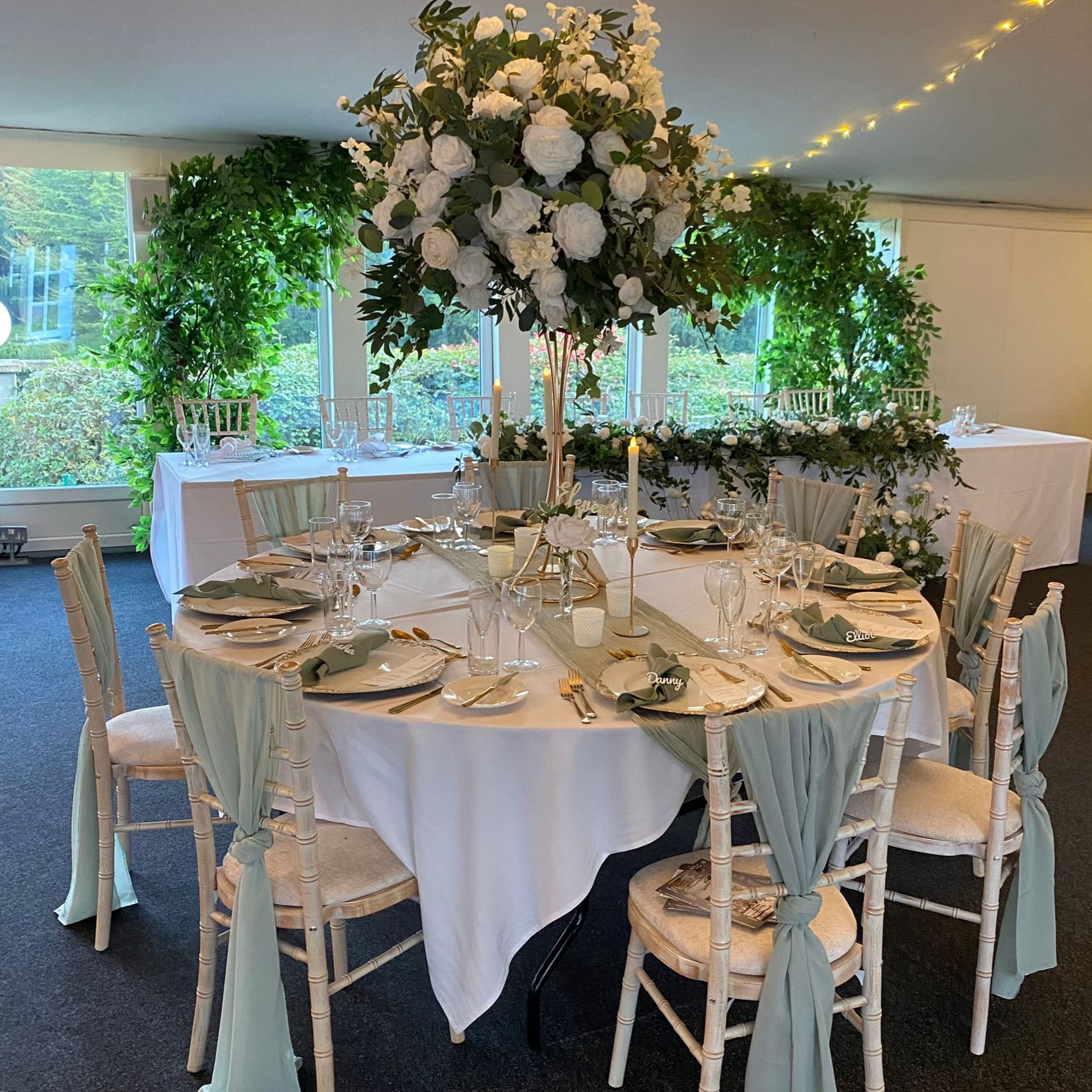 Green and white natural flowers with Sage cheesecloth runner and gold cutlery with white and gold charger plate
