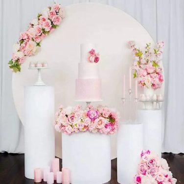 White gloss round cylinder plinths with pink flowers and cakes