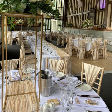 Champagne chair wraps with rectangular stands and cheesecloth runners
