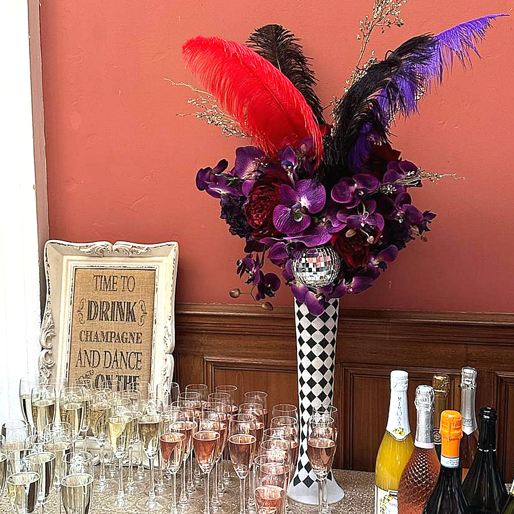 Circus Centrepiece Harlequin Vase with Purple & Red flowers feathers & mirror balls hire rent