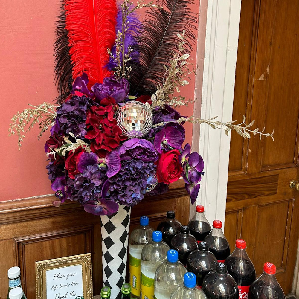 Circus Centrepiece Harlequin Vase with Purple & Red flowers feathers & mirror balls hire rent